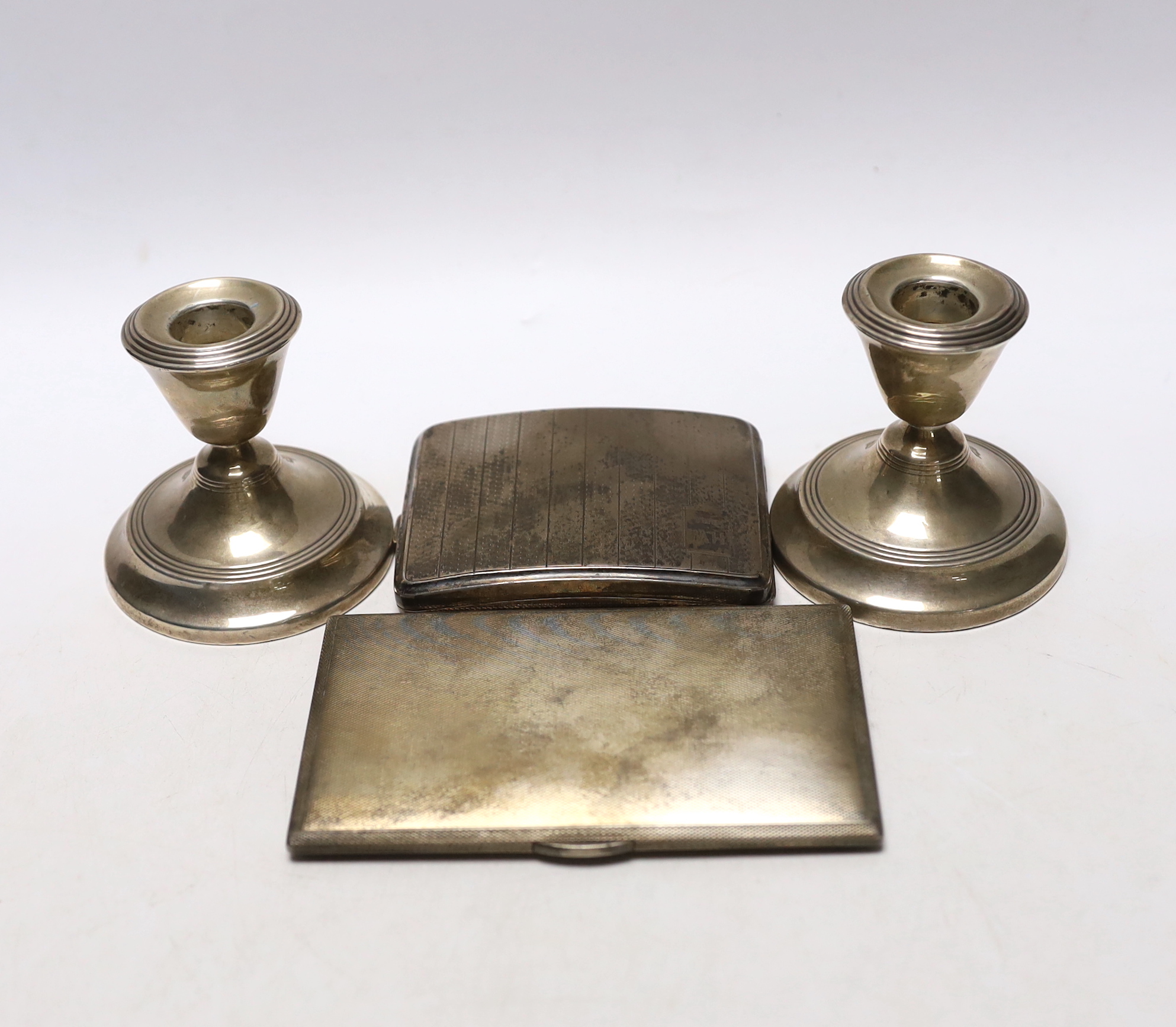 Two engine turned silver cigarette cases, largest 13.5cm and a pair of silver mounted dwarf candlesticks.